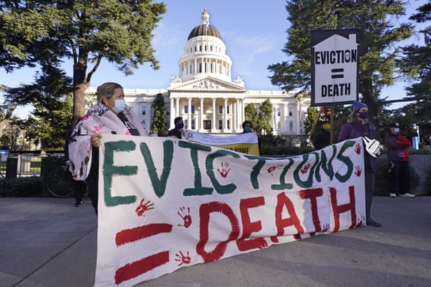 Demonstrators gather in front of the capitol building in Sacramento, California, holding a sign saying "Evictions = Death".