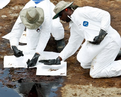 BP Plc contract workers are reflected in a pool of oil as they use absorbent pads to clean beach at Grand Isle State Park in Grand Isle, Louisiana, U.S., on Sunday, June 6, 2010