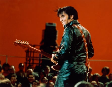 Elvis Presley performing on the Elvis comeback TV special on 27 June 1968, wearing black leathers and with his back to the camera, smiling at the crowd to his left