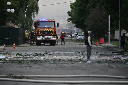 People walk among debris as firefighters intervene to put out the fire after drones strike on Kyiv.