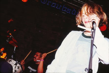 A young Beck sings into a microphone on stage