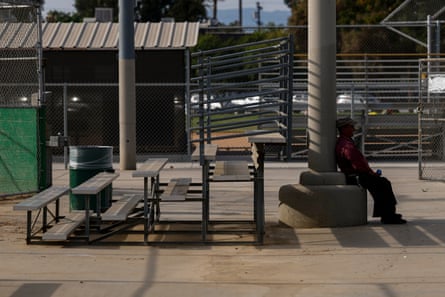 Marginally shaded outdoor area, with man sitting in strip of shade.