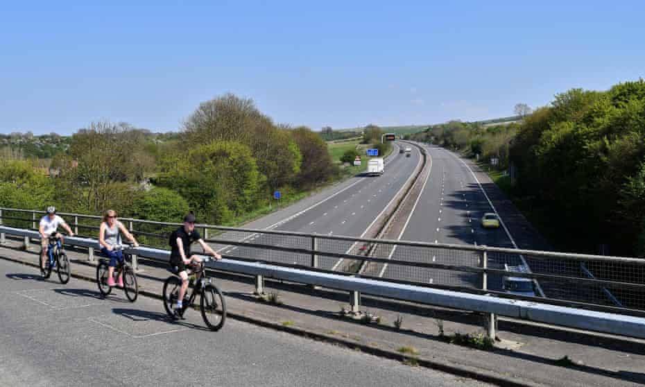 Cyclists cross a bridge over a quiet M4 motorway near Swindon in April