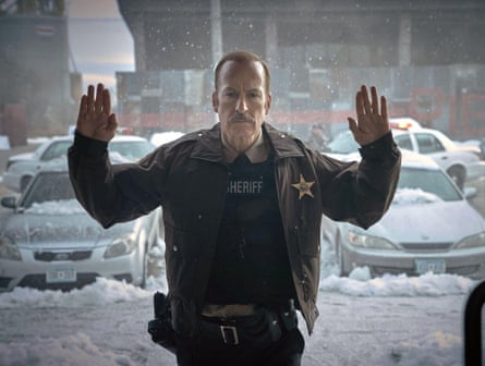In a sherriff’s uniform, Bob Odenkirk presses his hands and face against a plate-glass window from outside, where it is snowing