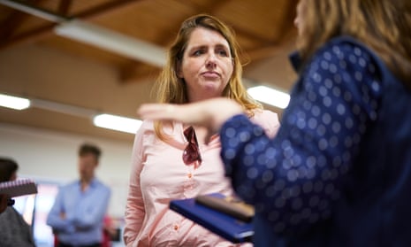 Alison McGovern, pictured in a pink shirt with sunglasses hooked over the top, talking to a woman at an employability centre,