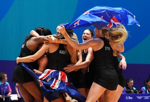 A group of women waging two large flags hug each other