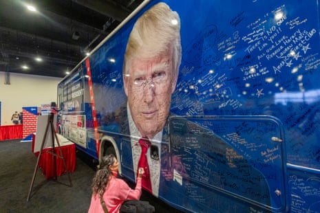 A woman signs a bus with a picture of former president Donald Trump on it during the Conservative Political Action Conference, CPAC 2024, at the National Harbor in Oxon Hill, Md., Friday, Feb. 23, 2024.
