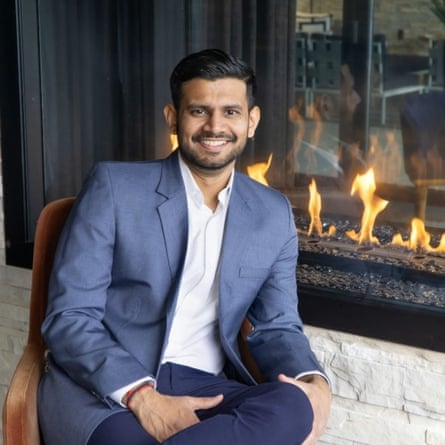 a man in a suit sits by a fire