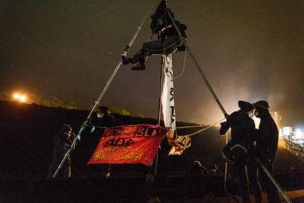 One of the activists sits atop a tripod near the conveyor belt of the plant during the blockade