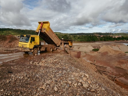 A truck tips its load into a pit.