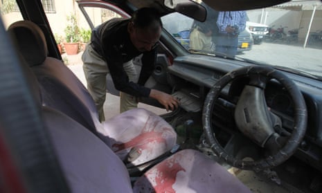 A Pakistani police officer examines a car of US citizen Debra Lobo, targeted by gunmen in Karachi on Thursday.