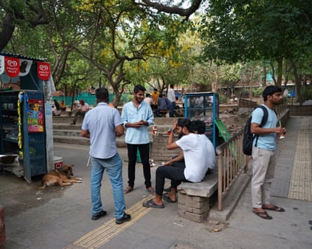 Male students standing or seated outside a small building selling refreshments