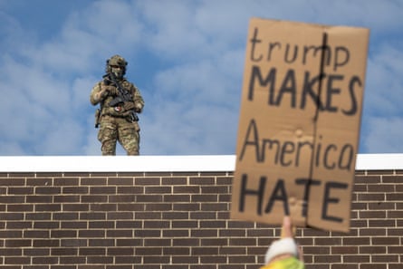 US federal police watch from the rooftop as demonstrators protest outside of an immigration processing centre in Broadview, Illinois on 12 September.