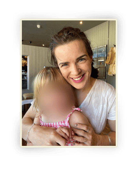 Matilda Davis smiles while hugging her young child, whose face is blurred