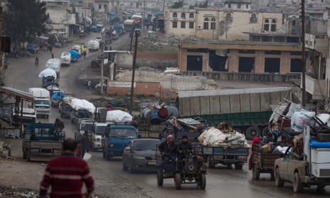 A convoy of vehicles taking Syrians to safety passes the village of Al-Mastuma, Idlib province,