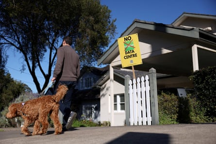 A man walking a dog passes a sign that says ‘No Goodman Data Centre’ outside a home in Lane Cove, Sydney, Australia