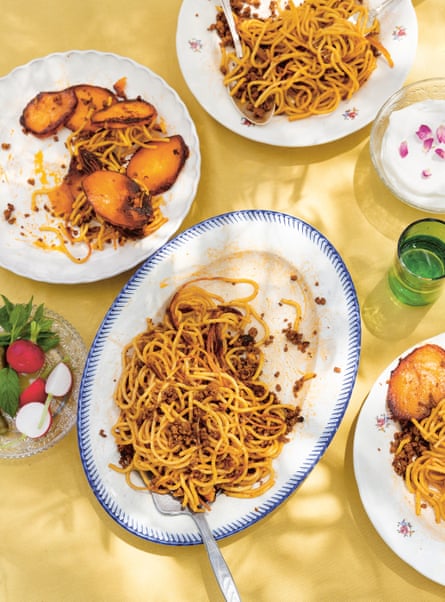 Top view of an oval dish with spaghetti with a meat sauce, on a yellow tablecloth, in dappled sunlight.