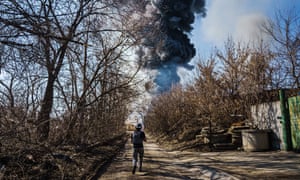 A photographer rushes ahead to photograph a building caught on fire after Russian bombardment hit several times in the area, in Moskovskyi district in Kharkiv, Ukraine, Friday, March 25, 2022.