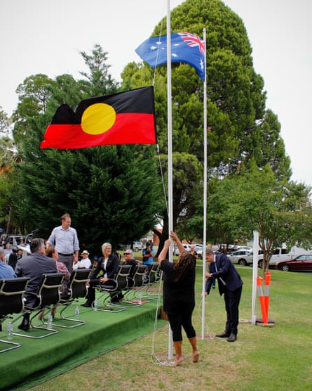 An Aboriginal flag is at half-mast next to a raised Australian flag