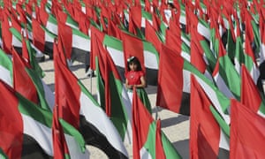 A girl walks inside a cluster of UAE flags. 