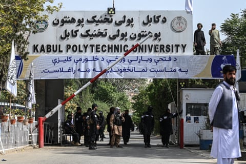 Men in black with guns at a gate under a sign saying Kabul Polytechnic University