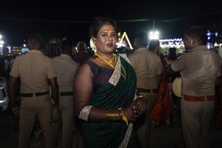 Akshaya in sari and gold jewellery standing in front of police officers at Koovagam festival