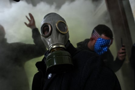 A man wears a gas mask while another wears an American flag mask during the capitol riot