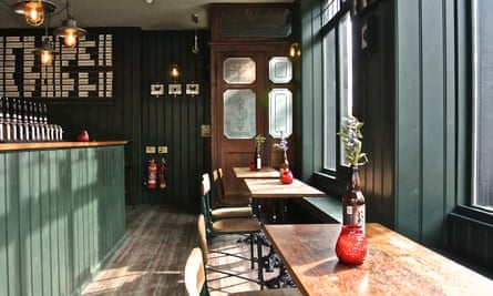 Sunlight comes through the windows in an interior image of tables and the bar at the Kings Arms, Bethnal Green, London