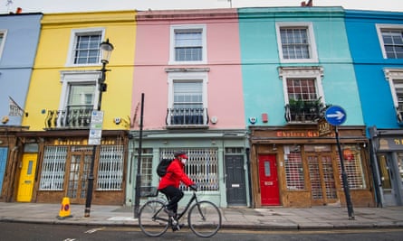 A cyclist wearing a face mask rides past closed up shops on Portobello Road in west London