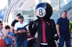 A man wearing a black suit with a red tie wearing an eight-ball helmet costume