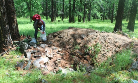 Archaeology student B. Byambajargal works to collect human bone, pieces of torn silk, and broken organic artifacts from a looted grave at Khorigiin Am in Khuvsgul, Mongolia.