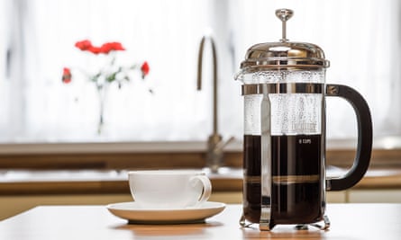 Cafetiere with cup and saucer on a kitchen worktop.