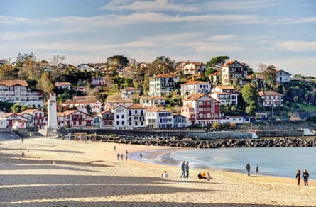 A sandy beach and a town rising up a hill behind it