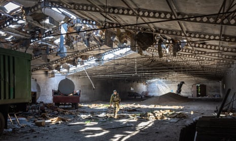 A Ukrainian soldier inspects a grain warehouse near Kherson after it was bombed by Russian forces.  