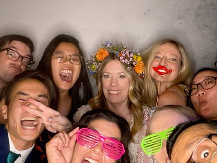 Tommy (bottom left corner in green tie) and his wife, Aimee (centre, in floral headpiece), in a group shot on their wedding day.