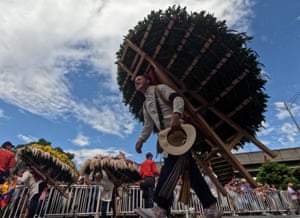 Farmers carrying large circular floral arrangements on their backs