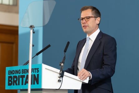 Robert Jenrick gives a speech in front of a sign that says: ‘Ending Benefits Britain’
