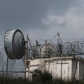 A low building with what looks like a satellite disk behind a fence with barbed wire