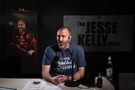 Man sits at a desk speaking into a microphone, with his radio show sign behind him