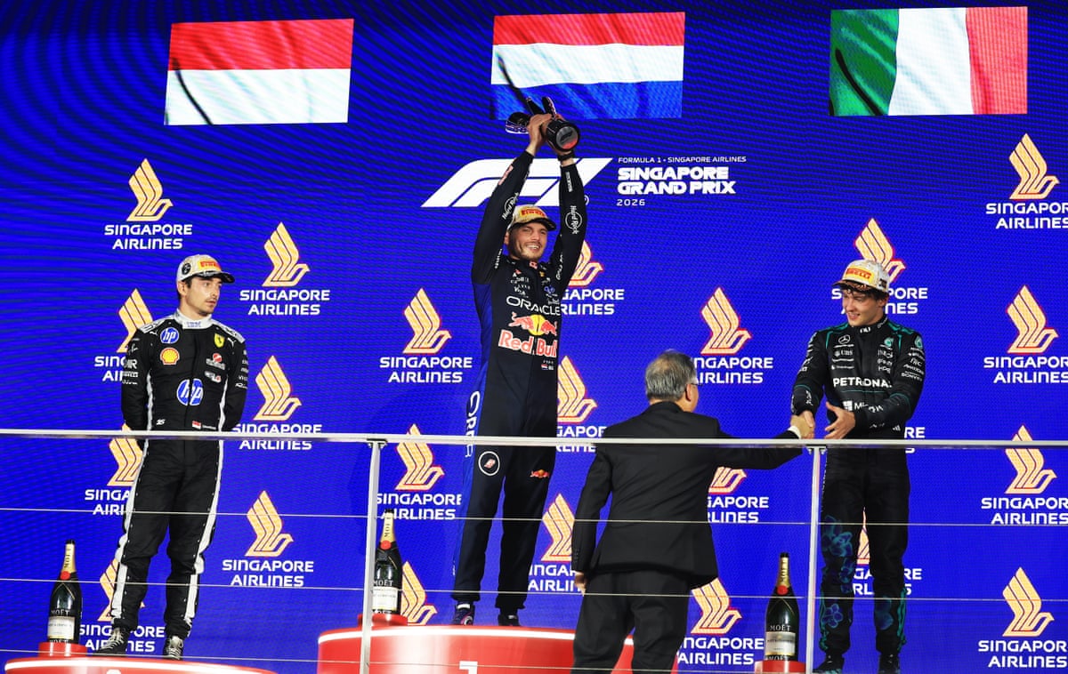 Max Verstappen holds the trophy aloft on the podiymn in Singapore, next of second-placed Charles Leclerc and third-placed Kimi Antonelli