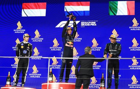 Max Verstappen holds the trophy aloft on the podiymn in Singapore, next of second-placed Charles Leclerc and third-placed Kimi Antonelli