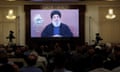 A screen showing Sayyed Hassan Nasrallah's televised address as a room full of people watch