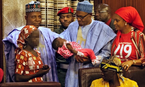 Nigerian president Mohammadu Buhari holds the daughter of the kidnapped Chibok schoolgirl Amina Ali, left.