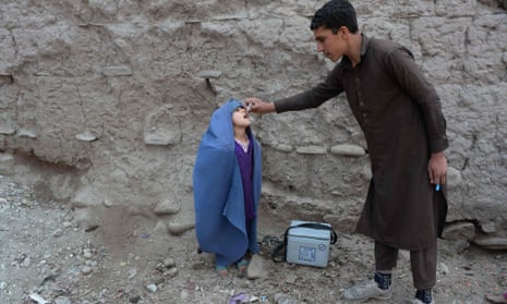 An Afghan health worker administers the polio vaccine to a child on the outskirts of Jalalabad