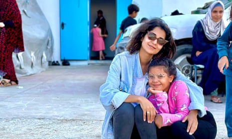 Jamileh Tawfiq, Palestinian journalist in Gaza, posing with a little girl, both wearing glasses.