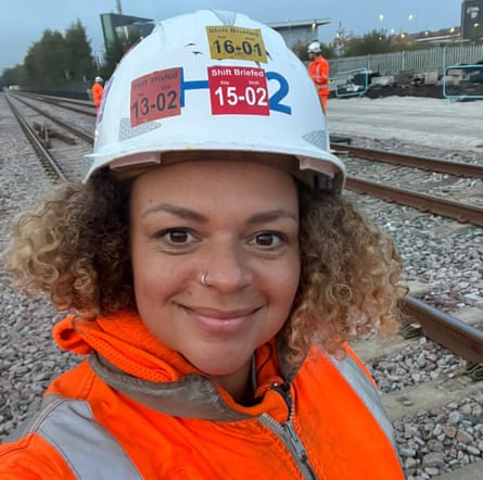 Reign Lawrence wearing a hi-vis jacket and hard hat while standing on a railway line with other workers behind her