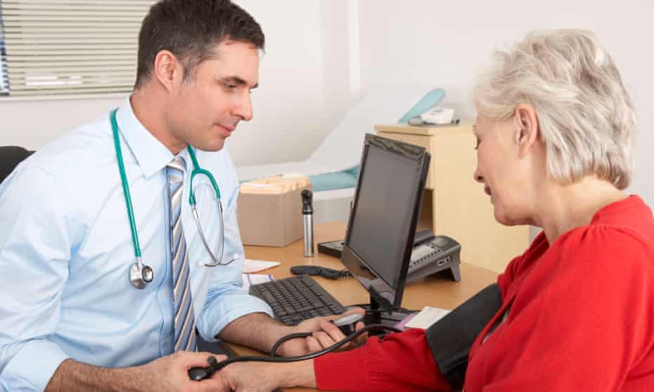 British doctor taking senior woman’s blood pressure
