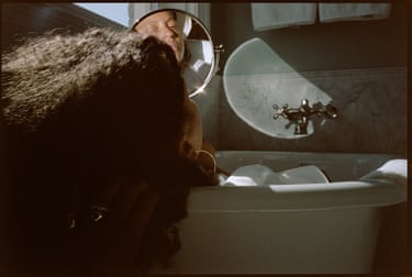 زنی که در وان حمام نشسته و به آینه نگاه میکند