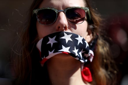 A woman wearing sunglasses and gagged with a stars and stripes bandana.