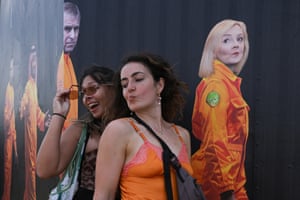 One reveller purses her lips to copy the expression on the face of the Liz Truss image behind her, while the other woman smiles